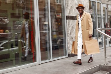 Alışveriş torbalarıyla dolu bir şehirde şık bir zenci.