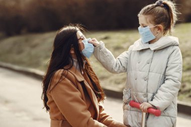 Anne ve kızı maskelerle dışarı çıkıyorlar.