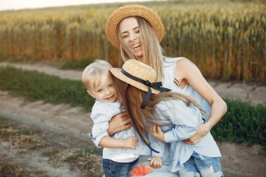 Anne ve çocuklar yaz tarlasında oynuyorlar.
