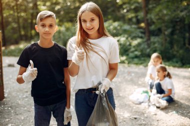 Çocuklar parktaki çöp torbalarında çöp topluyor.