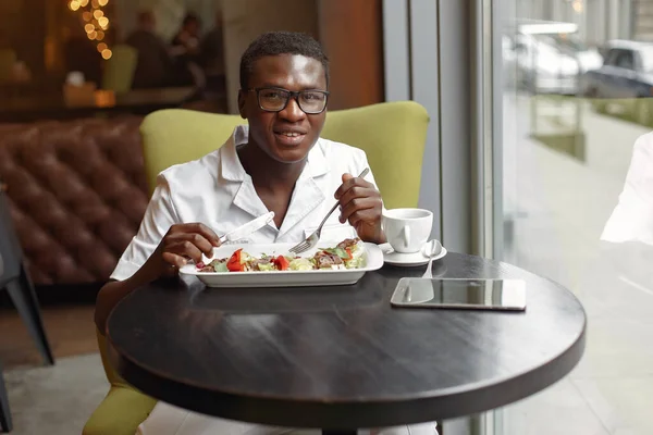 Schwarzer sitzt in einem Café und isst einen Gemüsesalat — Stockfoto