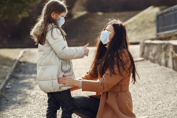 Madre con hija camina afuera con máscaras —  Fotos de Stock