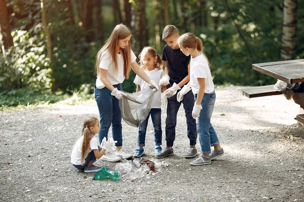 Crianças recolhem lixo em sacos de lixo no parque — Fotografia de Stock