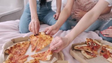 Kızların yatakta paylaştığı pizzanın yakın plan çekimi.