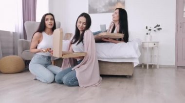 Güzel bayanlar yatak odasında pizza yiyor ve gülümsüyor.