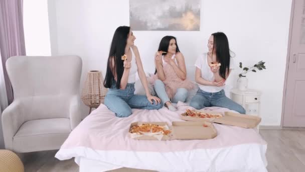 Три дівчини їдять піцу в ліжку і розважаються — стокове відео