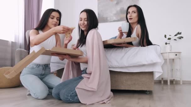 Las bellas damas están comiendo una pizza para llevar en el dormitorio y sonriendo — Vídeos de Stock