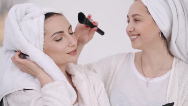 Two beautiful women with wrapped hair in towels are doing make-up — Stock Video