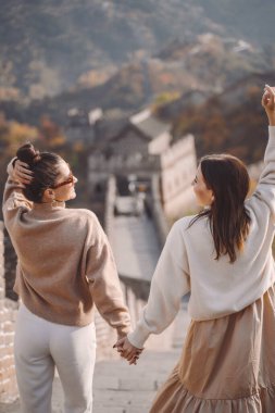 two female friends walking along the Great Wall of China near the Beijing entarnce clipart