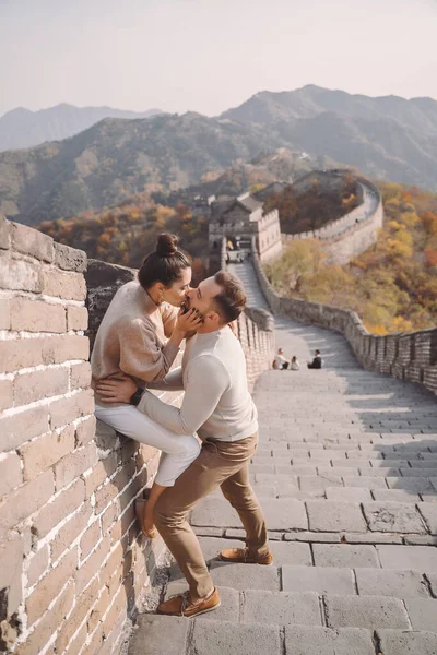 Belo jovem casal sentado e mostrando carinho na Grande Muralha da China . — Fotografia de Stock