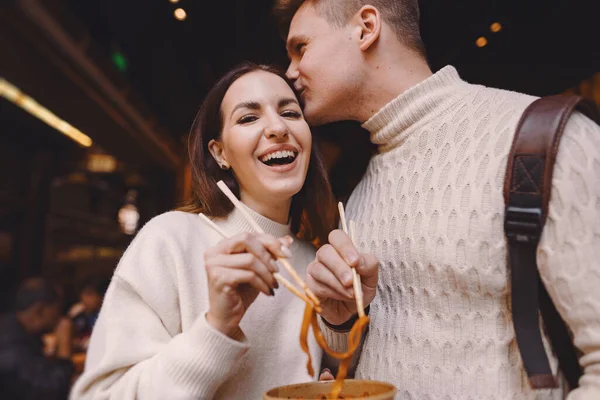 newlywed couple eating noodles with chopsticks in Shanghai outside a food market