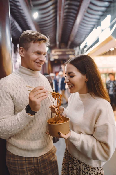 Pasgetrouwde echtpaar eet noedels met stokjes in Shanghai buiten een voedselmarkt — Stockfoto