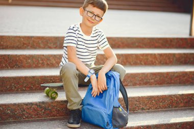 Sırt çantalı ve kaykaylı bir öğrenci.