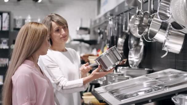 Žena a prodavačka si vybírají pánev v obchodě s nádobím. — Stock video