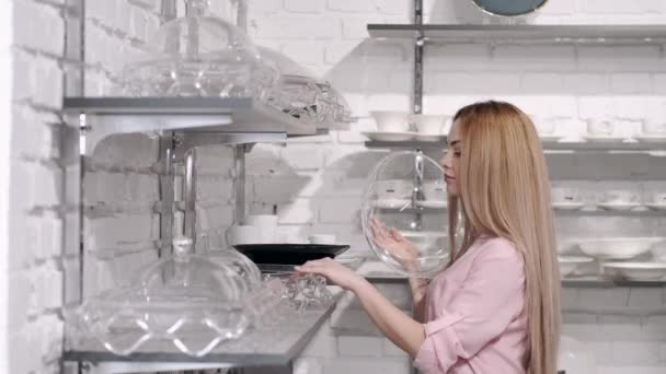 Женщина в посудной лавке выбирает стеклянный поднос с кепкой — стоковое видео