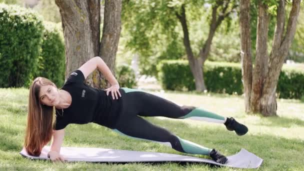 運動選手の女性は屋外で朝体操をしている — ストック動画