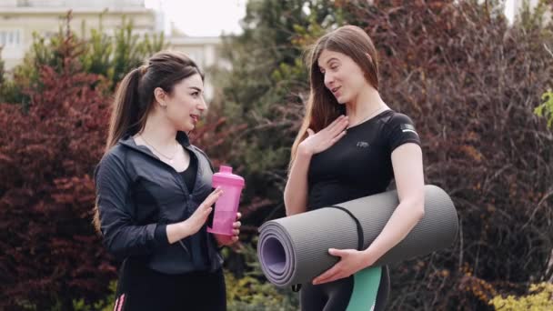 Досить спортивні дами зі спортивним обладнанням розмовляють надворі — стокове відео