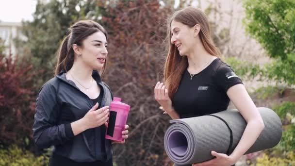 Ganska sportiga damer med sportutrustning pratar utanför — Stockvideo