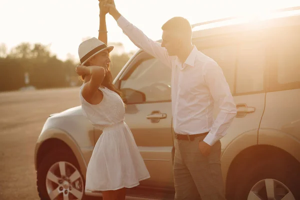 Beautiful couple spend time in a summer park near a car — 스톡 사진