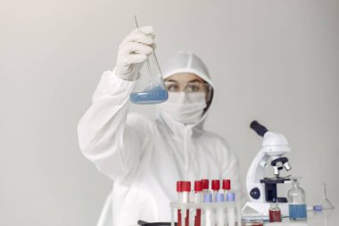 Bir laboratuvar bilimcisi mavi çözeltiyi şişede inceliyor.