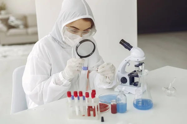 Cientista em roupas de macacão está examinando a amostra de coronavírus em um laboratório — Fotografia de Stock