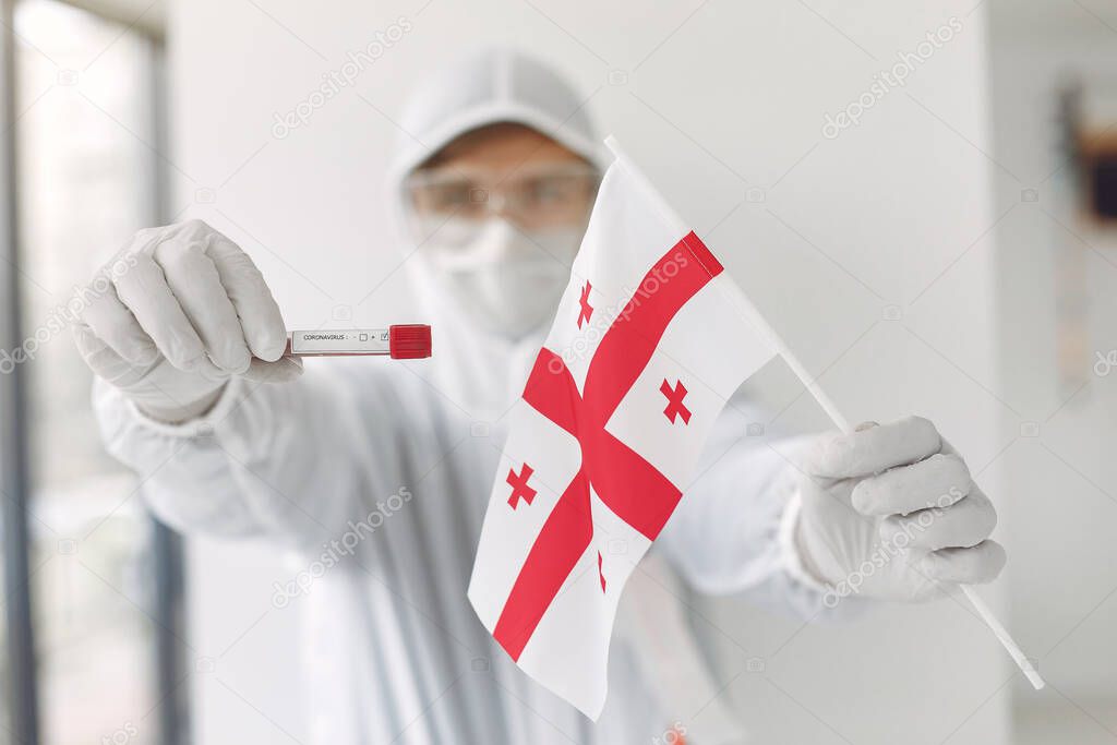 The scientist in coverall suit with a coronavirus sample and Georgian flag