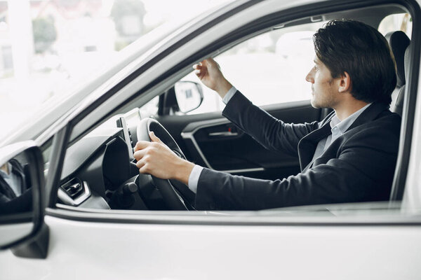 Handsome and elegant man in a car salon