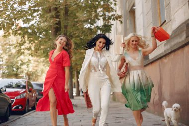 Şehirde alışveriş çantalı üç zarif kadın.