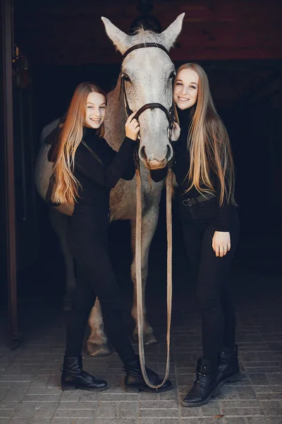 Meninas elegantes com um cavalo em um rancho — Fotografia de Stock