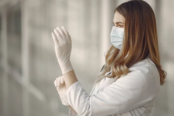 Mujer con máscara y uniforme se pone guantes —  Fotos de Stock