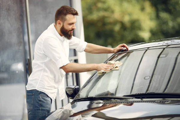 Pria berbaju putih menyeka mobil di tempat cuci mobil — Stok Foto