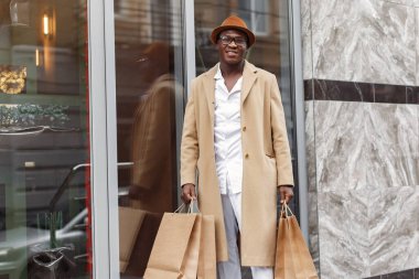 Alışveriş torbalarıyla dolu bir şehirde şık bir zenci.