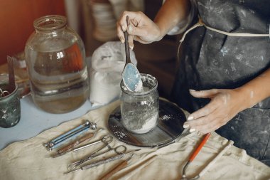 Genç bir kadın çömlekçide bulaşık yapıyor.