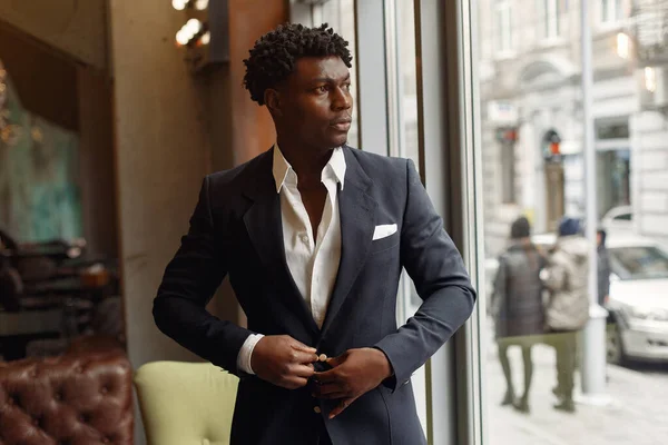 Black man in a black suit standing in a cafe