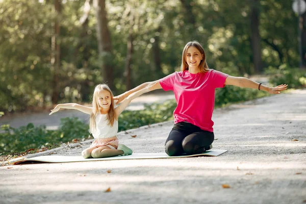 Мать с дочерью занимаются йогой в летнем парке — стоковое фото