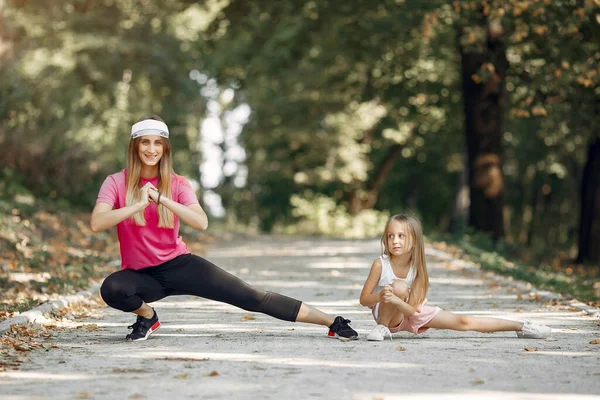 Anne ve kızı yaz parkında spor yapıyor.