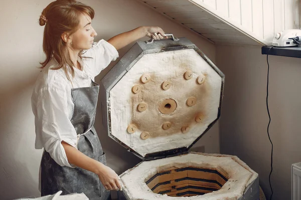 Een jonge vrouw maakt gerechten in een aardewerk — Stockfoto