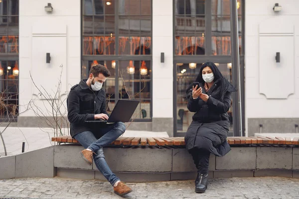 Gente con máscaras sentada en una ciudad con un portátil —  Fotos de Stock