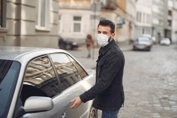 Hombre con una máscara de pie junto al coche en la calle —  Fotos de Stock