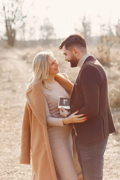 Gravid kvinna som står i en park med sin man — Stockfoto
