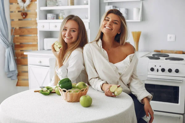 Meninas bonitas e desportivas em uma cozinha com um legumes — Fotografia de Stock