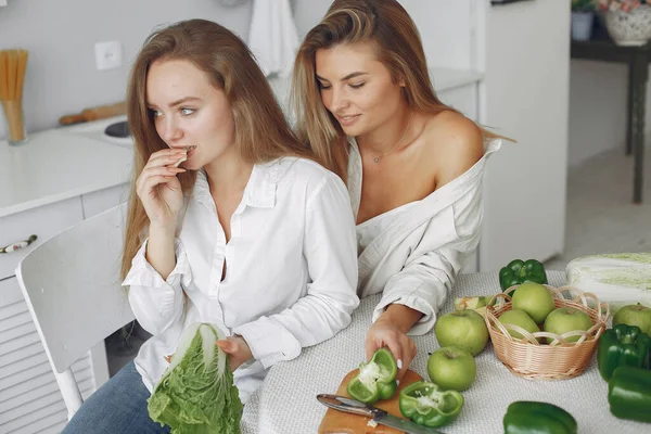 Meninas bonitas e desportivas em uma cozinha com um legumes — Fotografia de Stock