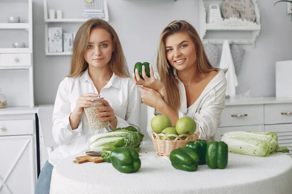 Krásné a sportovní dívky v kuchyni se zeleninou — Stock fotografie