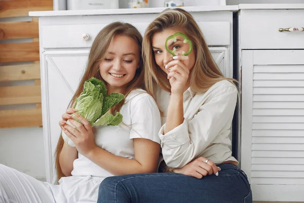 Meninas bonitas e desportivas em uma cozinha com um legumes — Fotografia de Stock