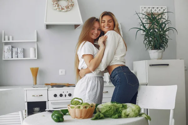 Vackra och sportiga tjejer i ett kök med grönsaker — Stockfoto