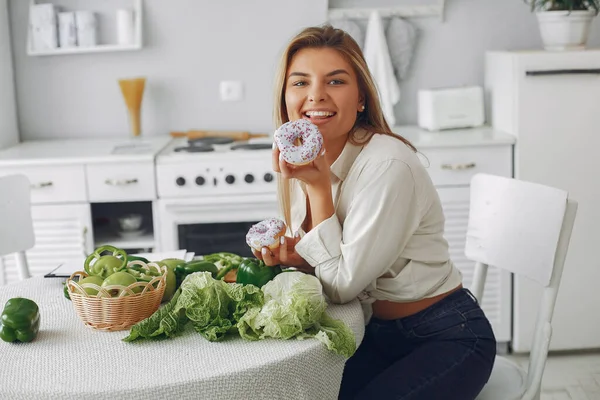 Vacker och sportig flicka i ett kök med grönsaker — Stockfoto