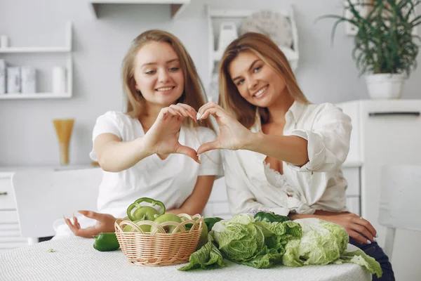 Meninas bonitas e desportivas em uma cozinha com um legumes — Fotografia de Stock