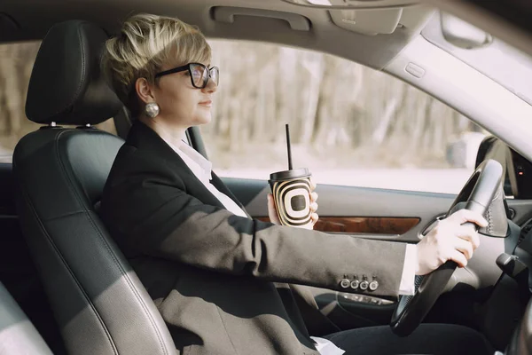 Donna d'affari seduta dentro una macchina e beve un caffè — Foto Stock