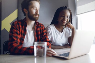 Birlikte çalışan gençler dizüstü bilgisayarlarını kullanıyorlar.