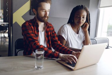 Birlikte çalışan gençler dizüstü bilgisayarlarını kullanıyorlar.